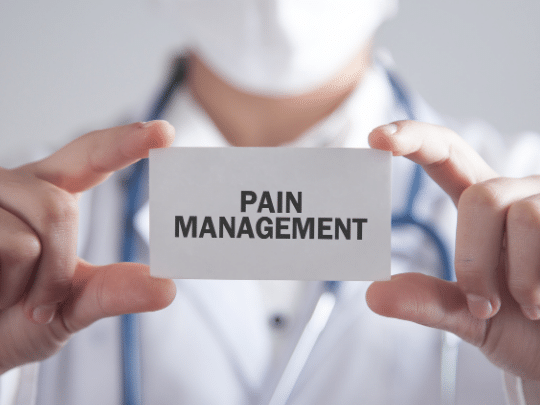 Physical therapist holding a card that says pain management